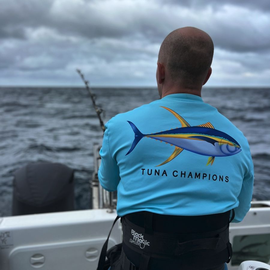 Barrett Wolfe, seen from behind in a Tuna Champions shirt, fishing from a game boat